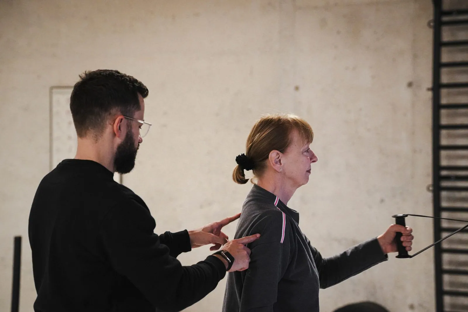 Personal Training in Heidelberg: Trainer korrigiert die Schulterhaltung an der Kabelzug-Station im BRIKS Studio