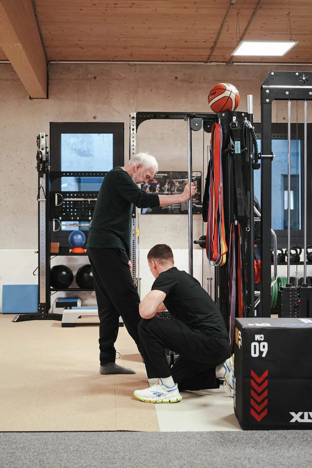 Trainingstherapie im BRIKS Studio Heidelberg: Betreuung eines Seniors bei einer Übung an der Kabelzug-Station