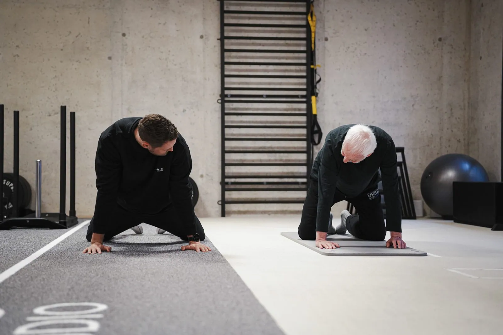 Seniorentraining im BRIKS Studio Heidelberg: Trainer zeigt eine Mobilisationsübung im Vierfüßlerstand